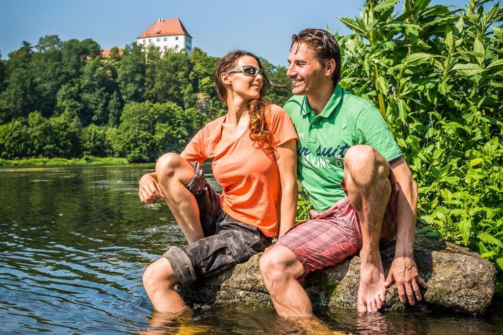 Ausflugspaar am Flussufer der Regen mit Schloss im Hintergrund